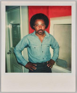 Oct 31 1976 [Man in denim shirt standing with hands on hips in red room]