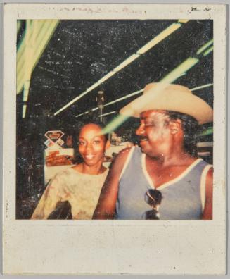 [Man in cowboy hat looking over his shoulder at smiling woman in store]