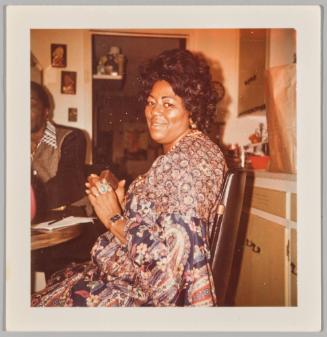 [Woman in paisley patterned dress sitting at table]
