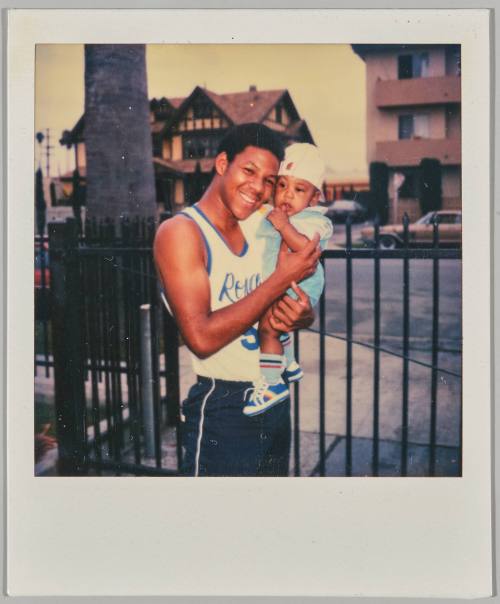 [Young man holding baby cheek-to-cheek]