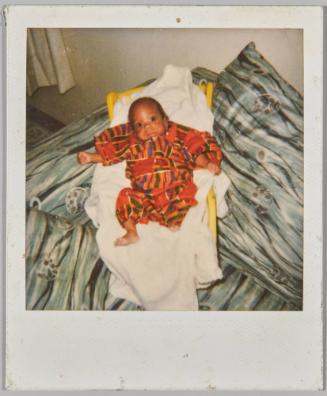 [Baby in multicoloured onesie laying in baby chair]
