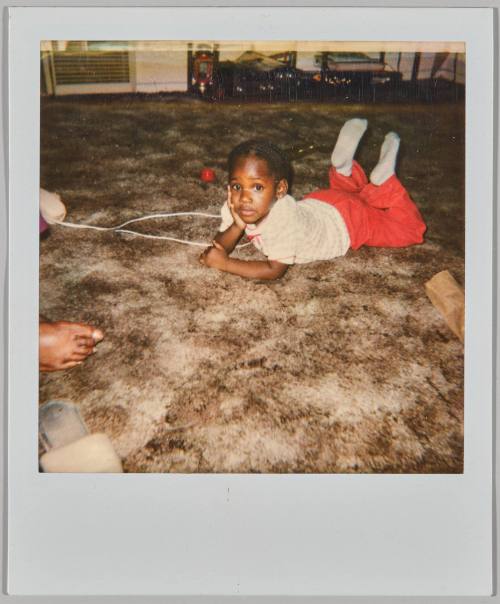 [Young girl laying on her stomach with one hand propped up under her chin]

