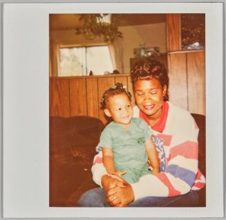 [Woman smiling with eyes closed holding toddler in her lap, toddler has blue hair accessories]

