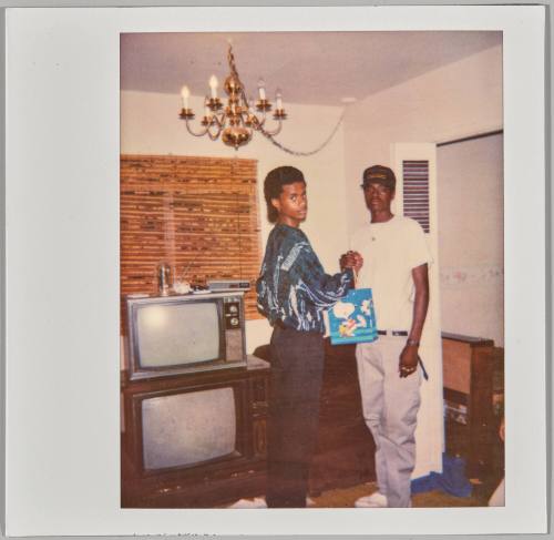 [Two adolescent boys bumping fists in living room, television to the left]
