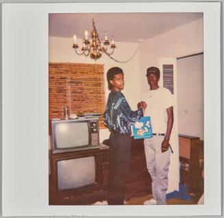 [Two adolescent boys bumping fists in living room, television to the left]
