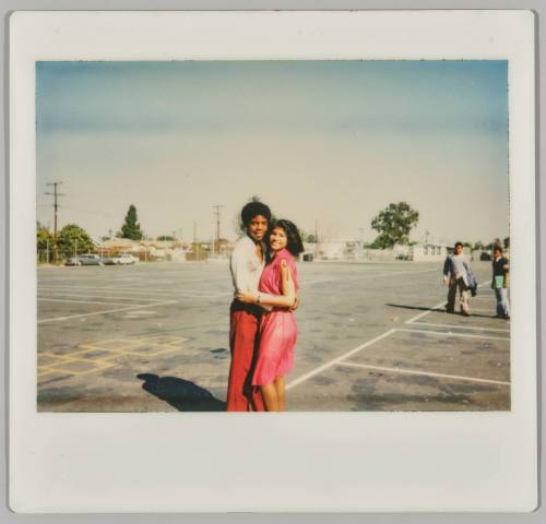 [Adolescent man and woman hugging in empty parking lot]
