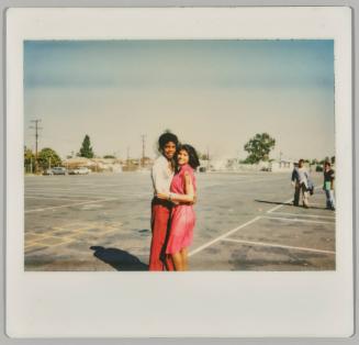 [Adolescent man and woman hugging in empty parking lot]
