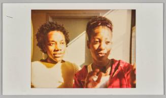 [Two young women standing in sunny room, woman on left wearing silver hoop earrings]
