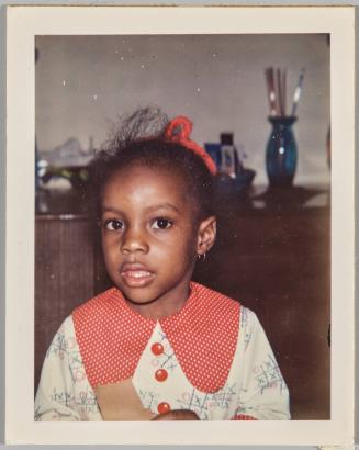 [Portrait of young girl wearing a button-up dress with a tic-tac-toe pattern on the fabric]
