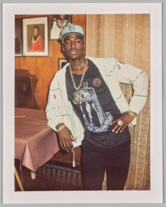 [Man wearing Batman graphic t-shirt leaning against table]
