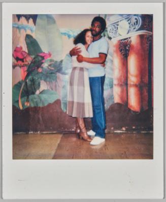 March 85 [Man and woman hugging in front of painted mural on back wall]
