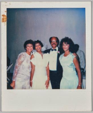 [Bride with wedding guests posing together and smiling, woman on right wearing light blue dress]
