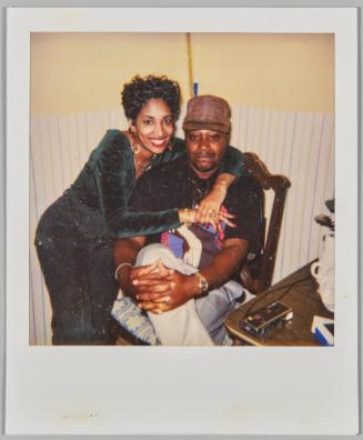 [Woman with arms around man sitting on chair]
