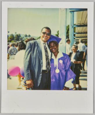 [Man posing with arm around teenage girl in purple cap and gown]
