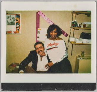 [Man sitting in chair as woman leans against him, woman wearing a Playboy sweatshirt]
