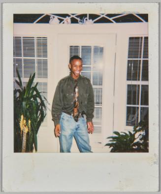 [Man in tie smiling in front of white panelled doorway with plants on either side]
