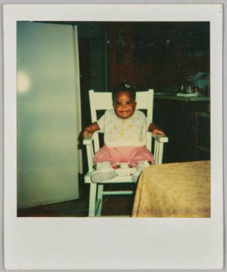 [Baby sitting in chair with bib and boots on]
