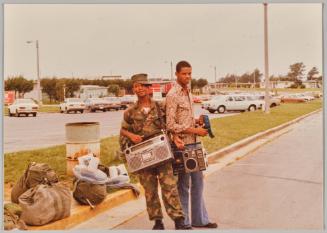 [Two men posing and holding boomboxes]
