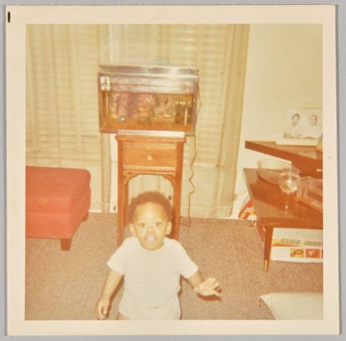 1970 [Toddler standing in living room, fish tank in the background]
