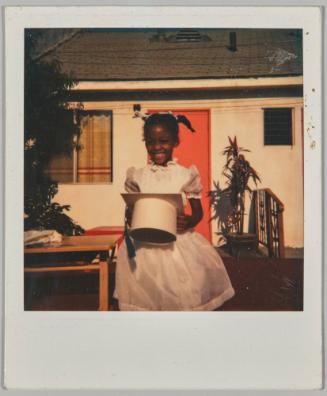 [Little girl in white dress holding white graduation cap]
