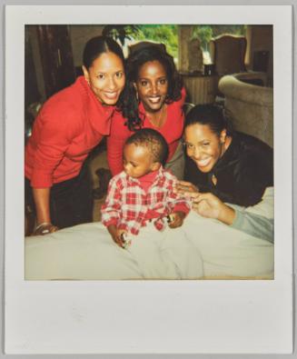 [Three women posing with little boy in red]
