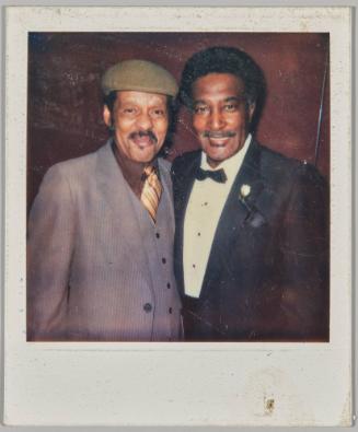 [Two older men posing, man on left in brown suit]
