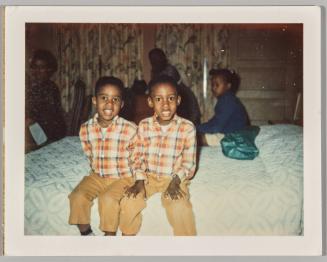 [Little boys sitting on bed wearing matching plaid shirts]
