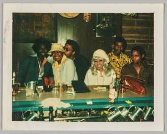 [Group sitting at a bar, woman in  middle wearing a silver blonde wig]
