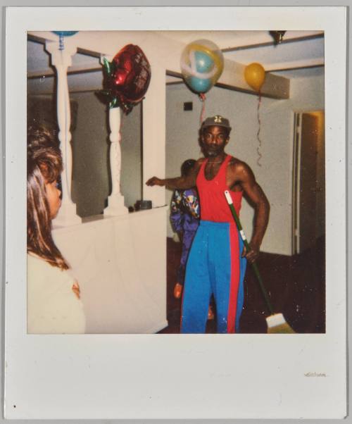 3-10-93 [Man holding broom in house with balloons]