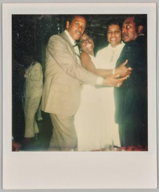 [Two men embracing two women from either side at formal event]
