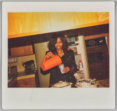 [Woman in kitchen pouring liquid from pitcher into cup]
