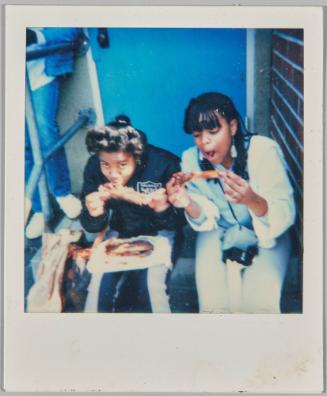 [Two teenage girls eating pizza on staircase]

