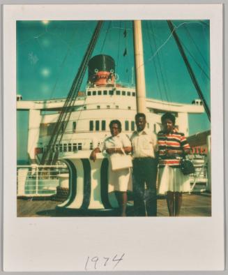 July 1974 [Two women and man posing in front of boat]