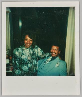 [Woman in blue floral dress sitting on man's lap]

