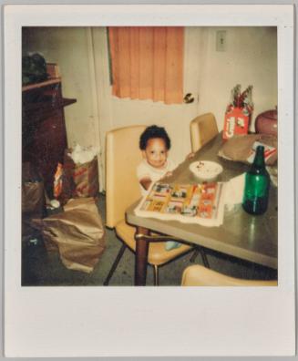 [Toddler sitting at table with newpaper and white plate on table]

