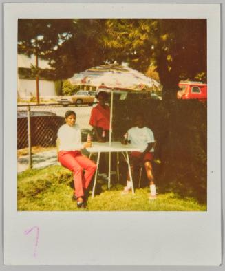 [Three young women sitting at table outdoors with umbrella drinking beers]
