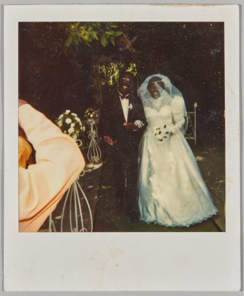 [Bride and groom posing outdoors with flower arrangements]
