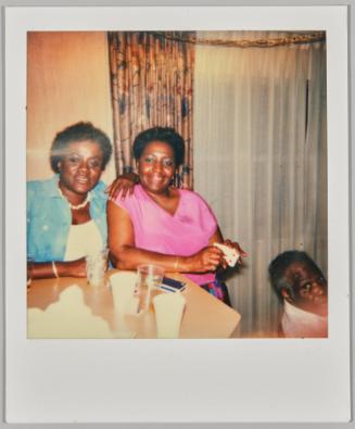 [Two women posing at table with deck of cards in hand]
