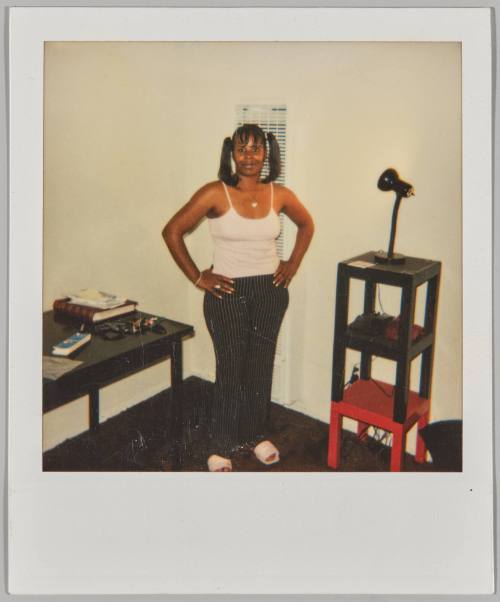 [Woman with pigtails standing next to desk with hands on hips]
