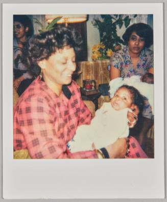 [Woman holding baby in arms with another woman holding baby in background]
