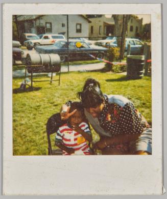 [Woman and child at barbeque, woman making peace sign]
