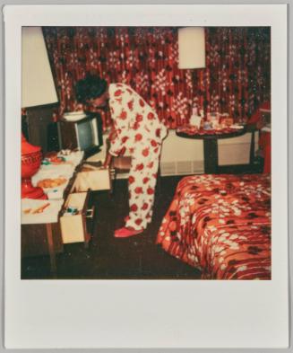 [Woman in pajamas going through dresser drawers in bedroom]
