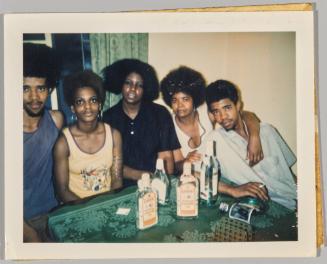 [Two men and three women sitting at table with bottles of gin]
