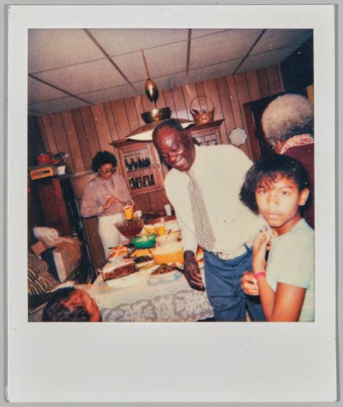 [Man, woman and child in dining room with large meal displayed on table]
