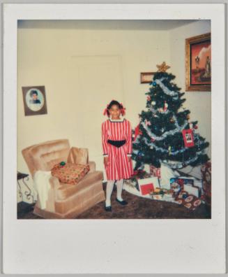 [Girl in pinstriped red dress in living room with Christmas tree]
