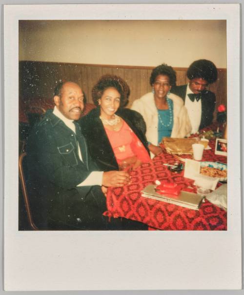 [Two men and two women dressed formally sitting at table]
