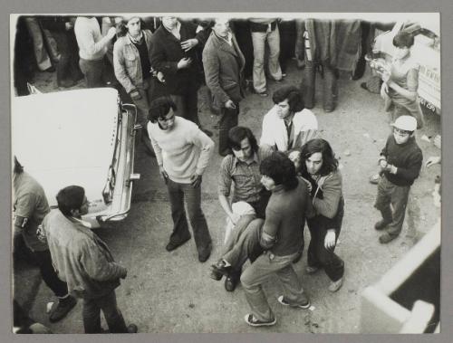 [A group of men carrying an injured woman to safety]
