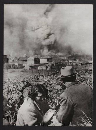 Two civilians looking on as city burns.