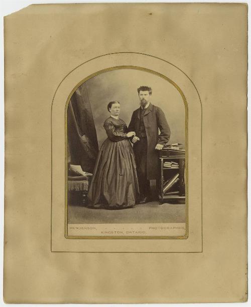 [Couple standing by bookshelf]