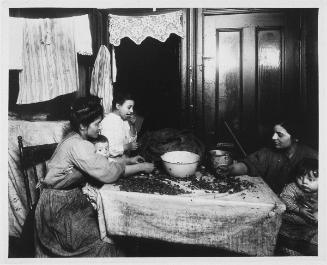 East Side, New York City (Tenement family picking out nut-meat…),